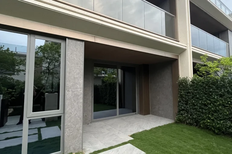 Premium private residence in Foshan by China Overseas Land, with large thermal-break aluminium sliding glass doors opening onto a stone-clad terrace and lawn